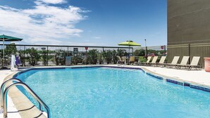 Une piscine avec une rambarde en métal, des chaises longues et des parasols.
