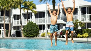 A swimming pool with two children jumping in the air.