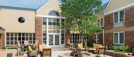 A courtyard with outdoor seating, a fire pit, and a large windowed entrance.