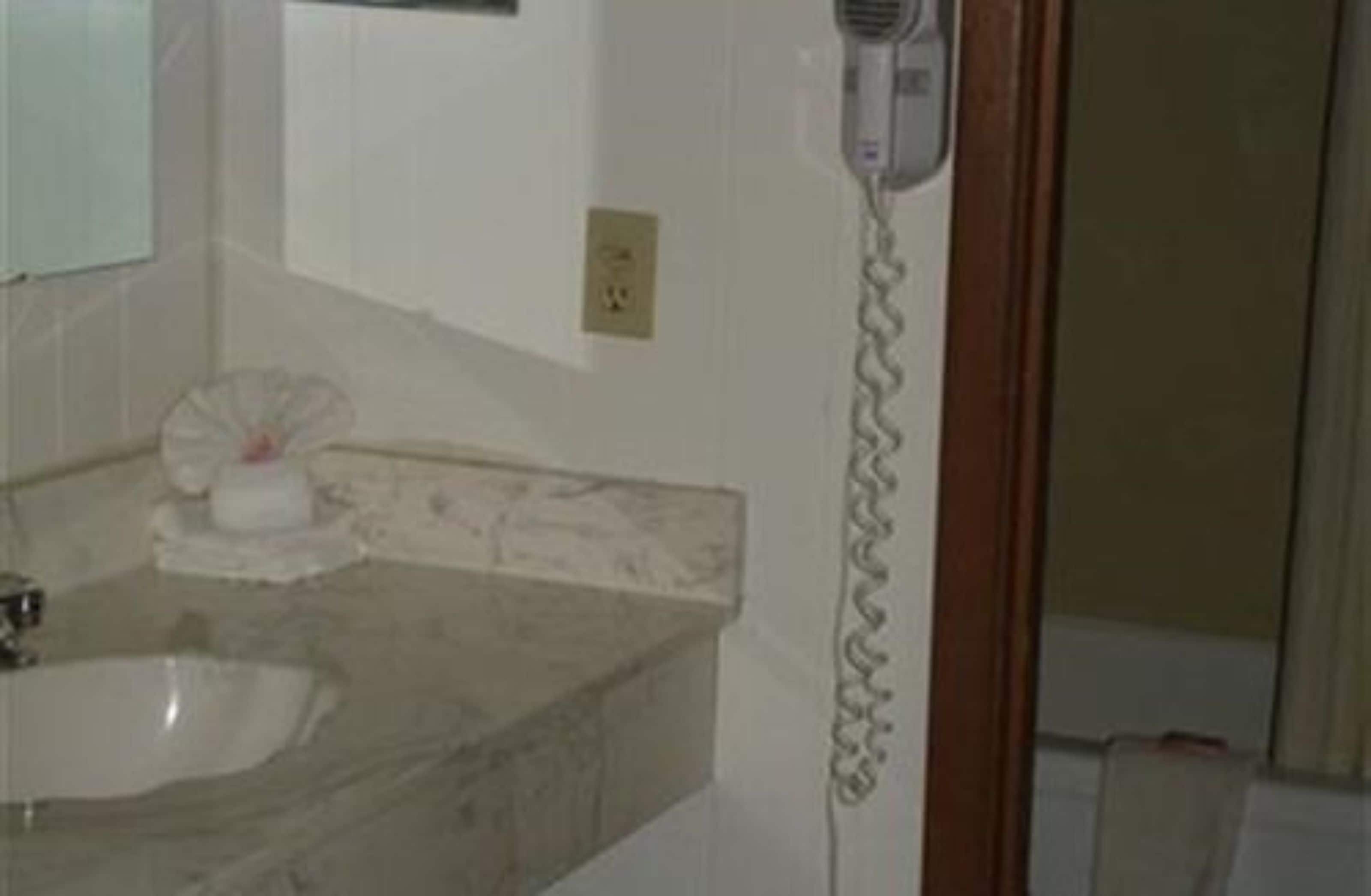 A bathroom with a sink, a hairdryer on the wall, and a towel rack.