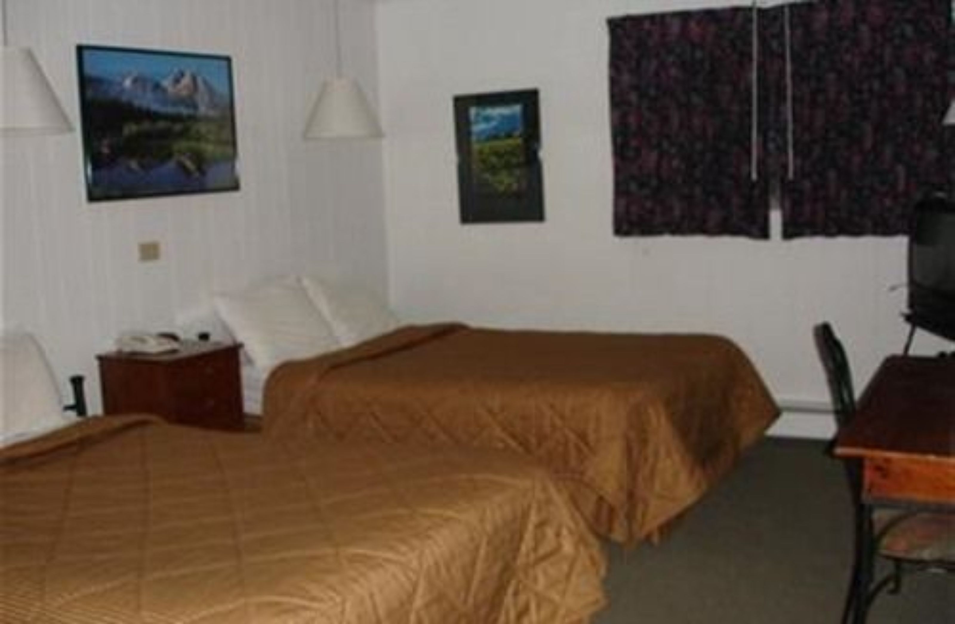 Habitació d'hotel amb dos llits, una taula de treball i una cadira. Hi ha dos quadres al mur.