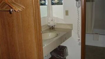 A bathroom with a wooden door, a sink, a mirror, and a telephone.