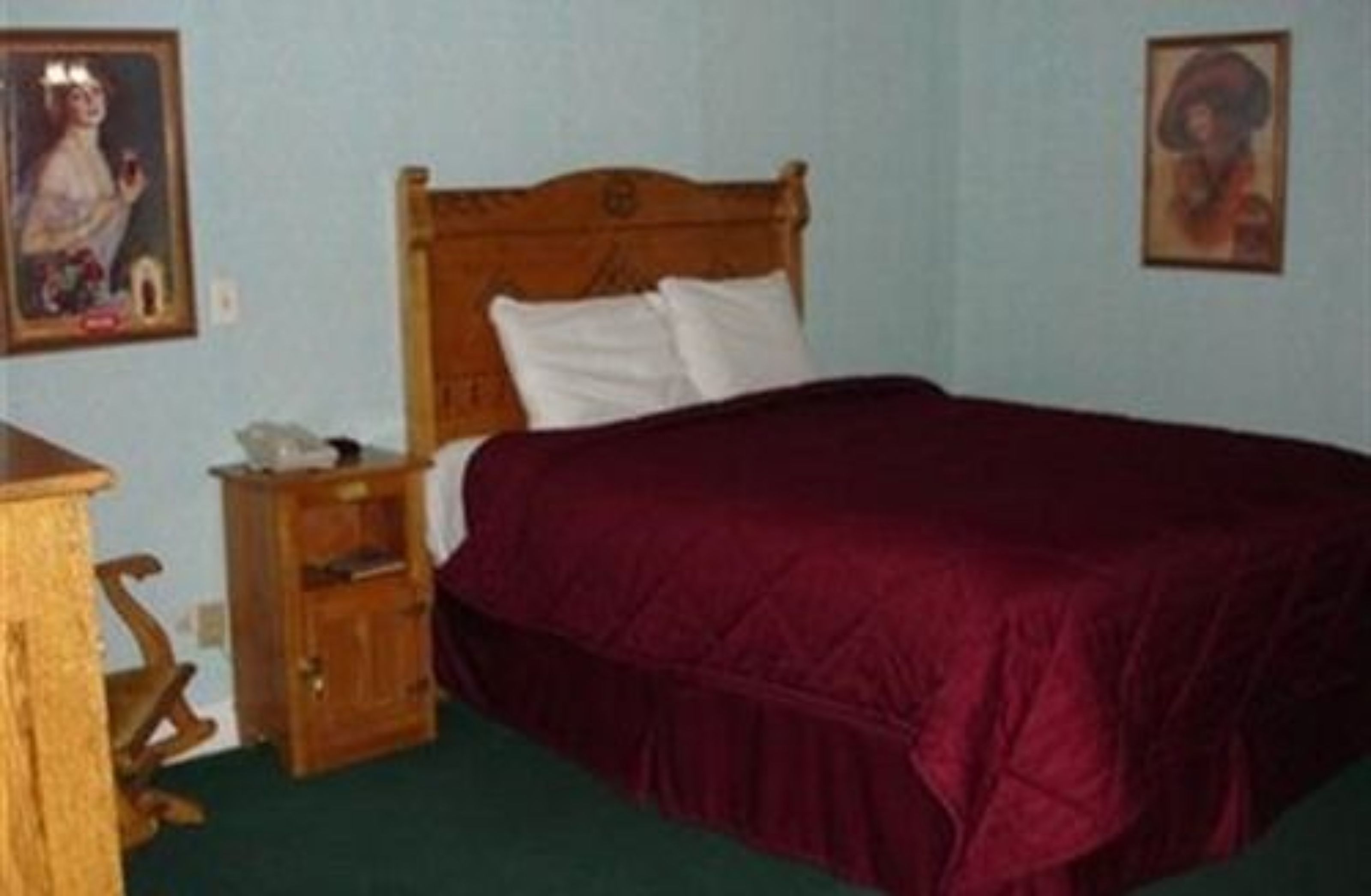 Ein Schlafzimmer mit einem hölzernen Bett, einem Nachttisch und zwei gerahmten Bildern an der Wand.