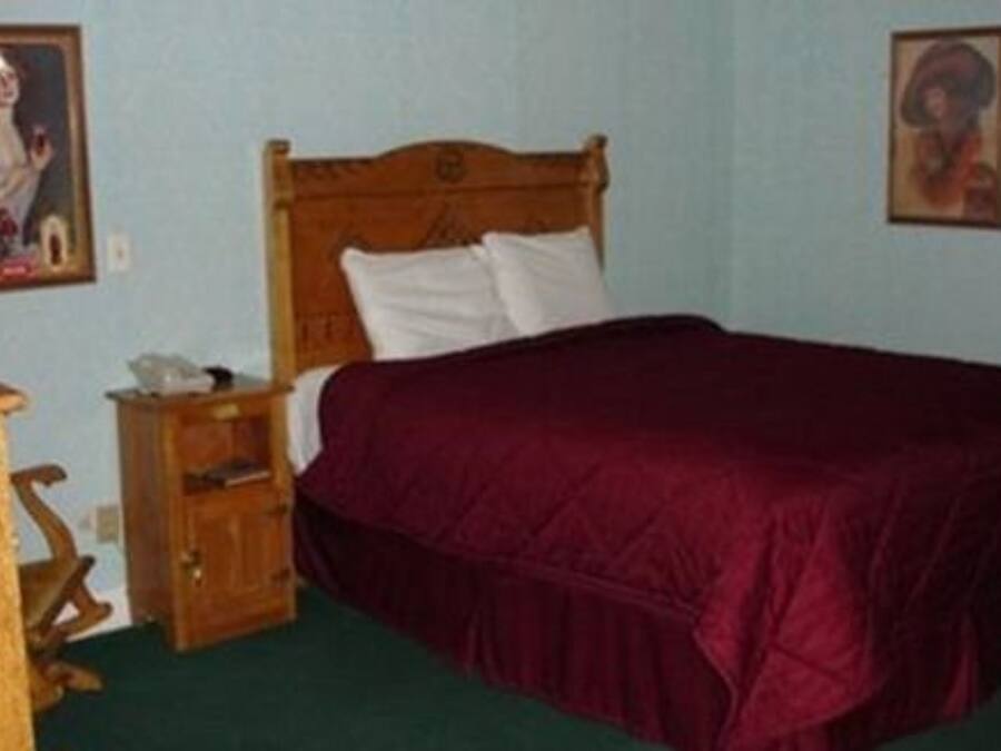 Ein Schlafzimmer mit einem hölzernen Bett, einem Nachttisch und zwei gerahmten Bildern an der Wand.