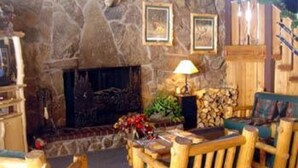 A cozy room with a stone fireplace, wooden furniture, and framed pictures on the wall.