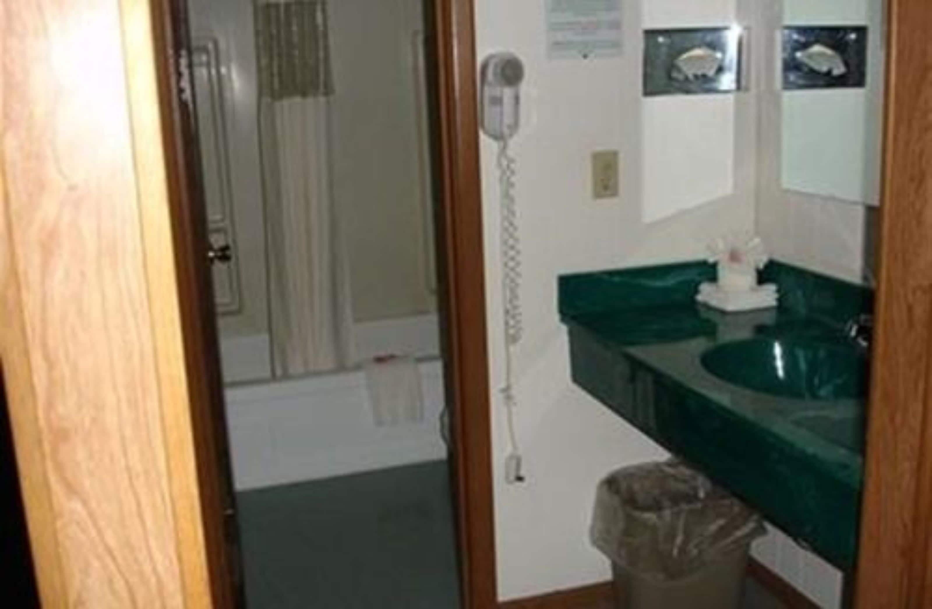 A bathroom with a green sink, a mirror, and a shower.