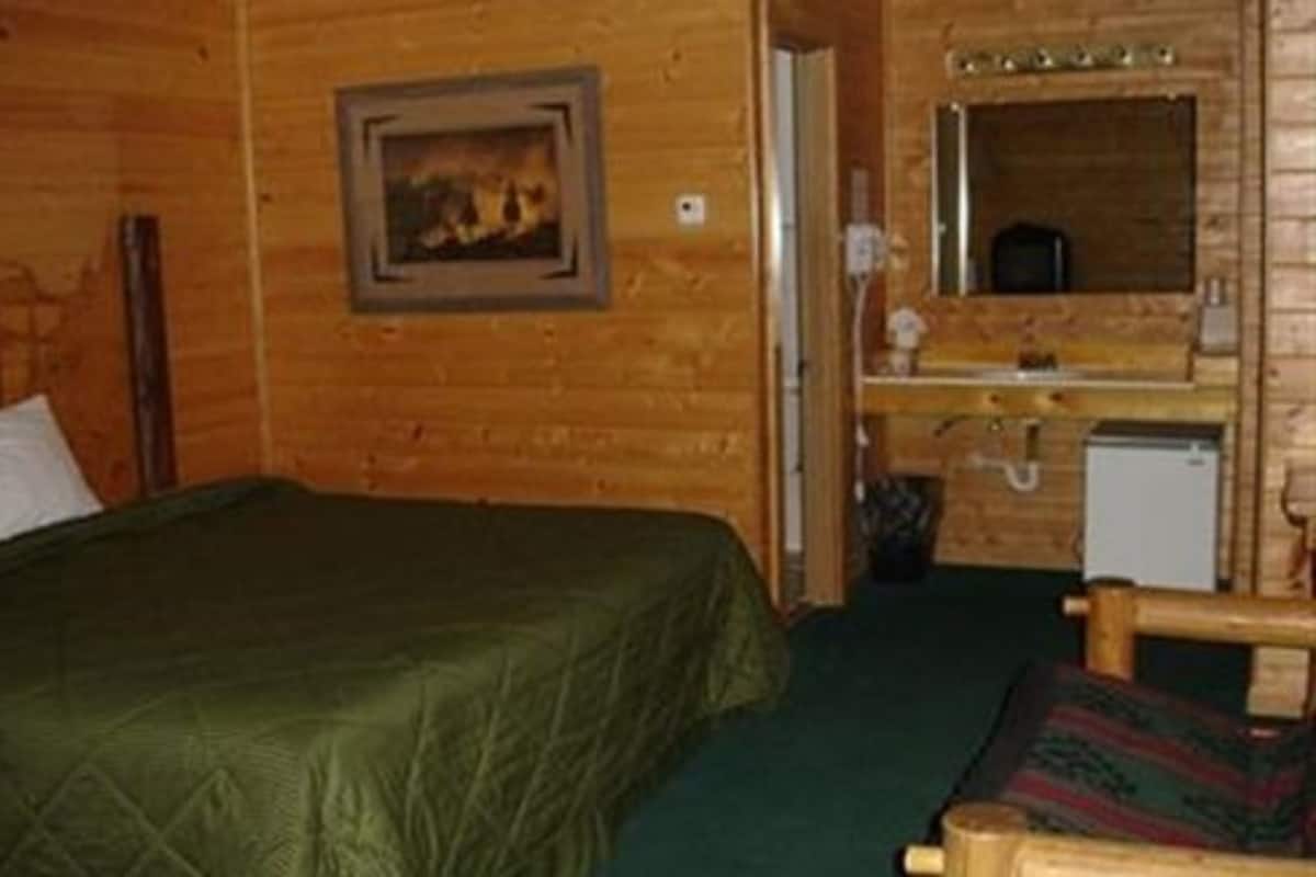 Quarto de cabana de madeira com cama, pequena escrivaninha e espelho.