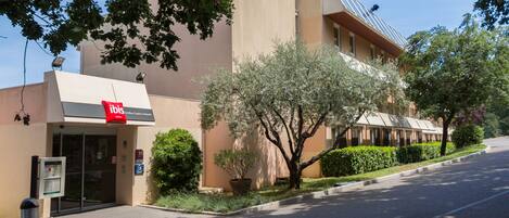 A hotel entrance with a clear driveway, a reception desk, and a signboard.