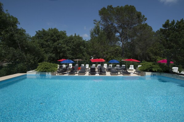 Una piscina al aire libre, sillones reclinables de piscina