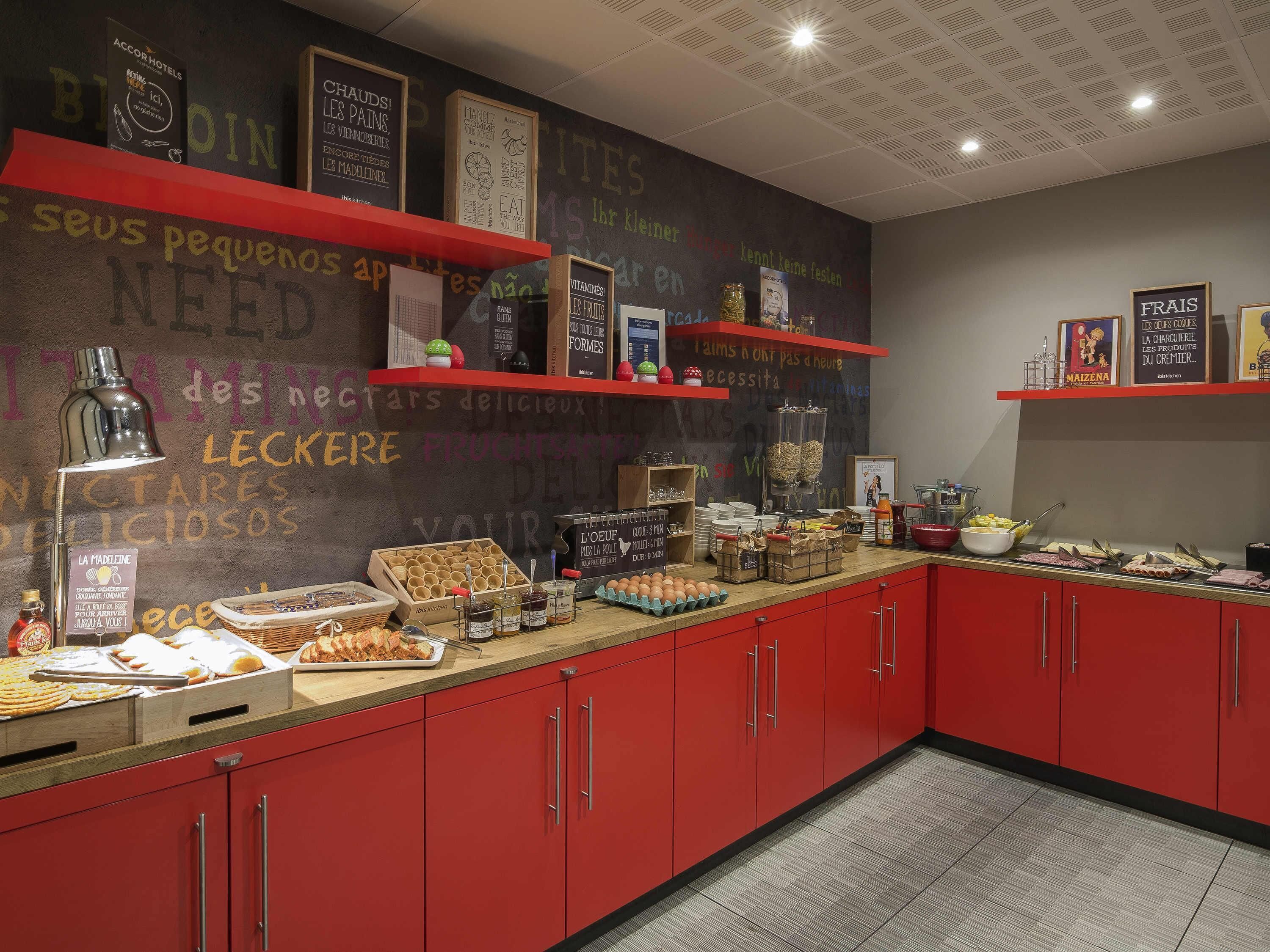 A kitchen area with red cabinets, a chalkboard wall with various writings, and food items displayed on the counter.
