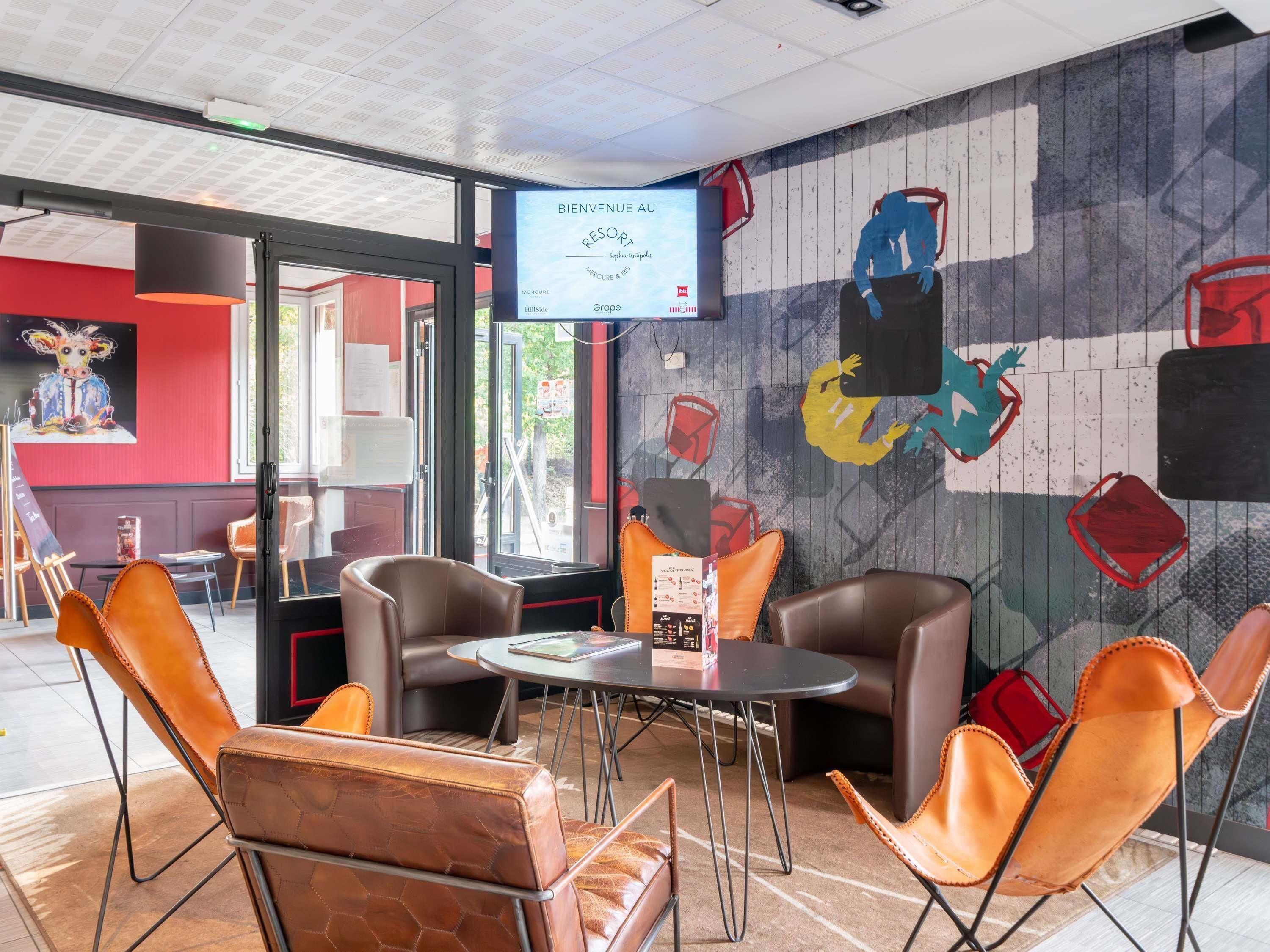 A modern interior with leather chairs, a round table, and a mural on the wall.