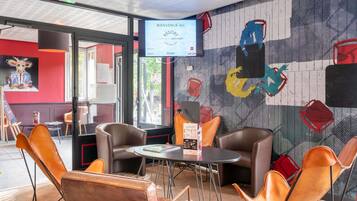 Decoração moderna com poltronas de couro, uma mesa redonda e um mural na parede.