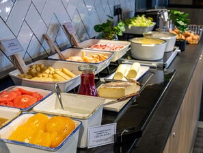 Een buffet met diverse gerechten, zoals fruit, kazen en sauzen.