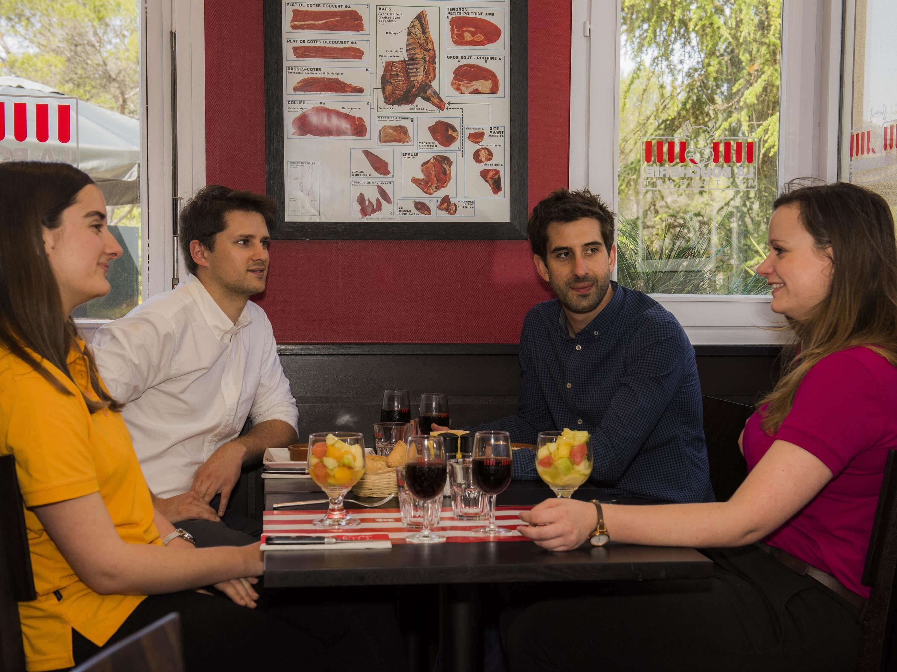 Um grupo de pessoas sentadas à mesa, com um menu e vista para a janela.