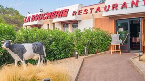Un restaurante llamado 'La Boucherie' con una estatua de vaca en la entrada, rodeado de follaje.