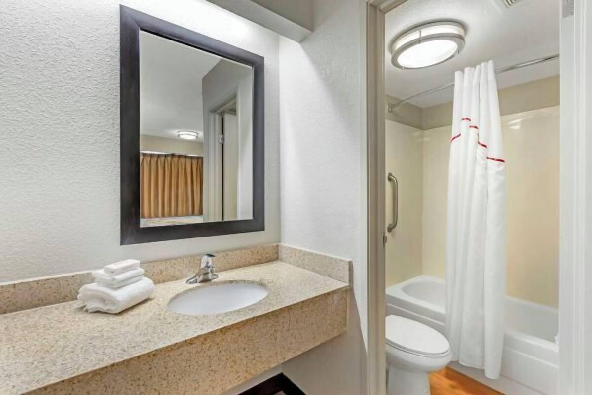 A bathroom with a sink, mirror, and shower.