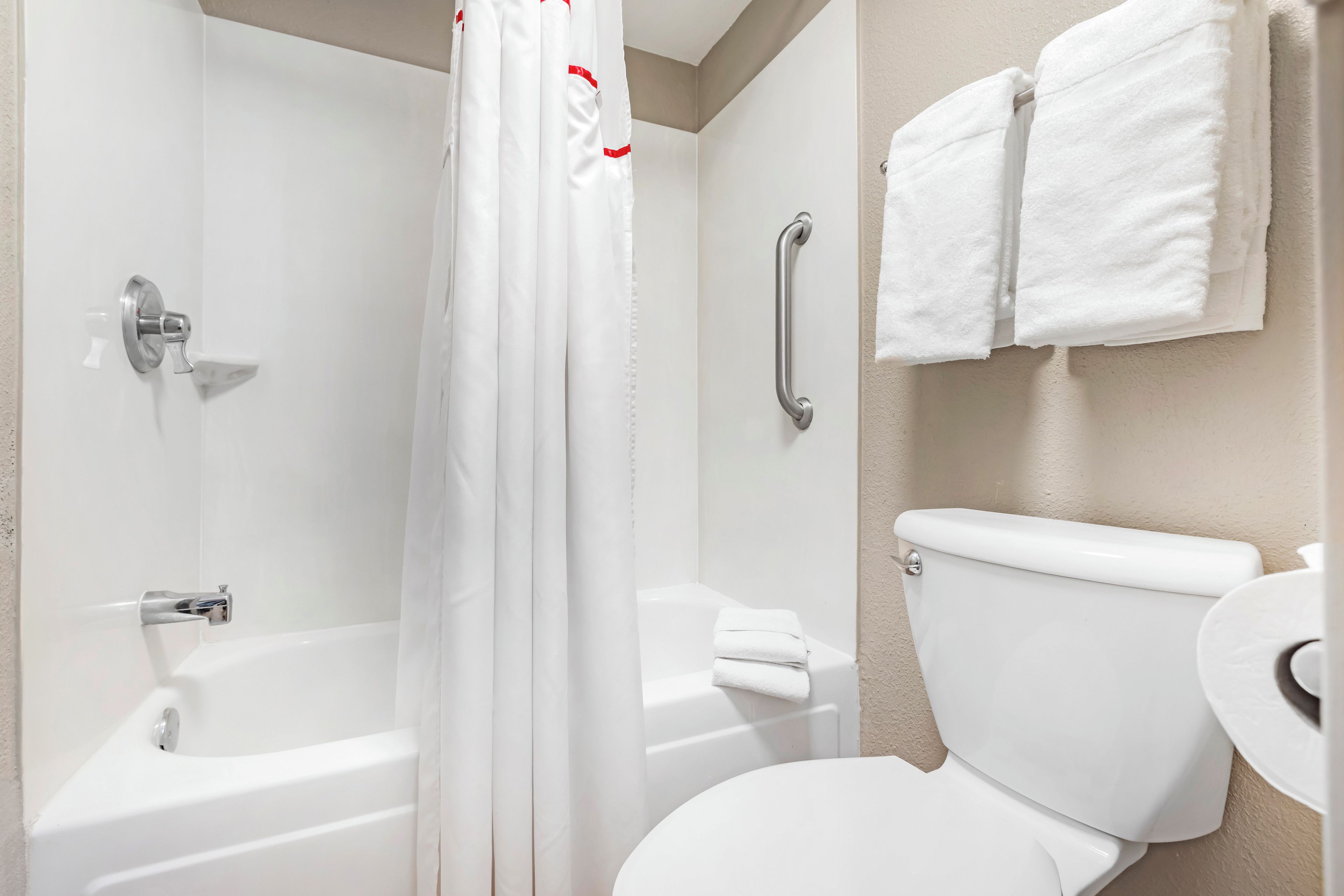 A bathroom with a bathtub, a toilet, and a shower curtain.