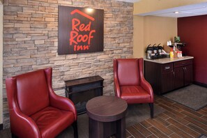 Red Roof Inn -hotellin aula, jossa on kiviseinät, nahkaverhoillut nojatuolit, pieni pyöreä pöytä ja kahvinautintoalue.