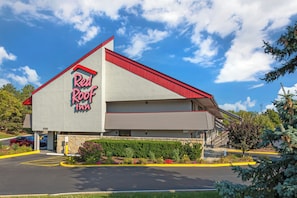 A Red Roof Inn with a red roof, a stone facade, and a parking lot with yellow curbs.