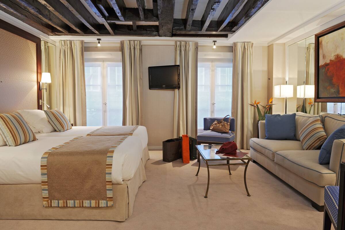 A hotel room with a large bed, a sofa, a small table, and a television.