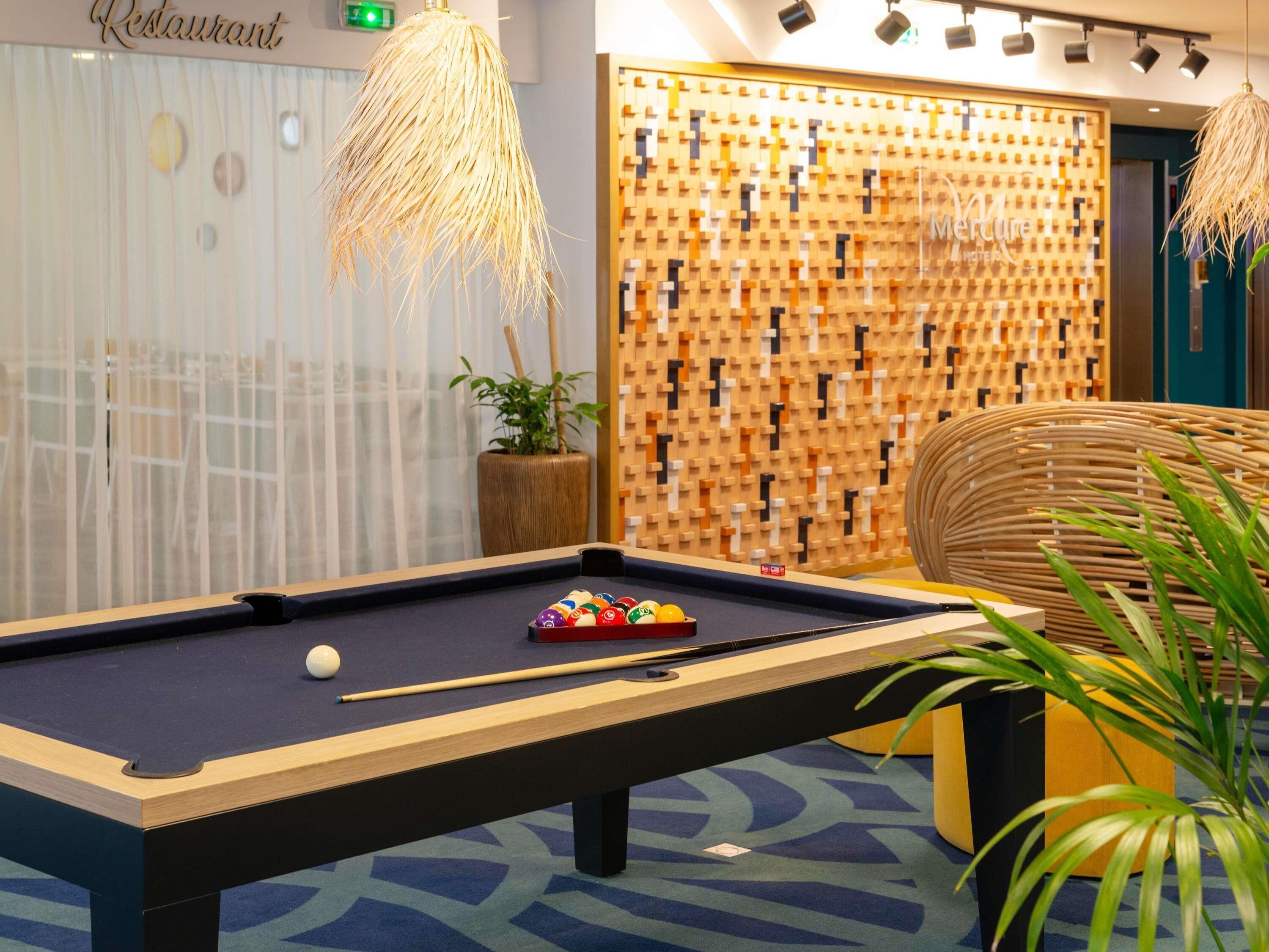 A pool table with balls, a lounge chair, and a wall with a geometric pattern.