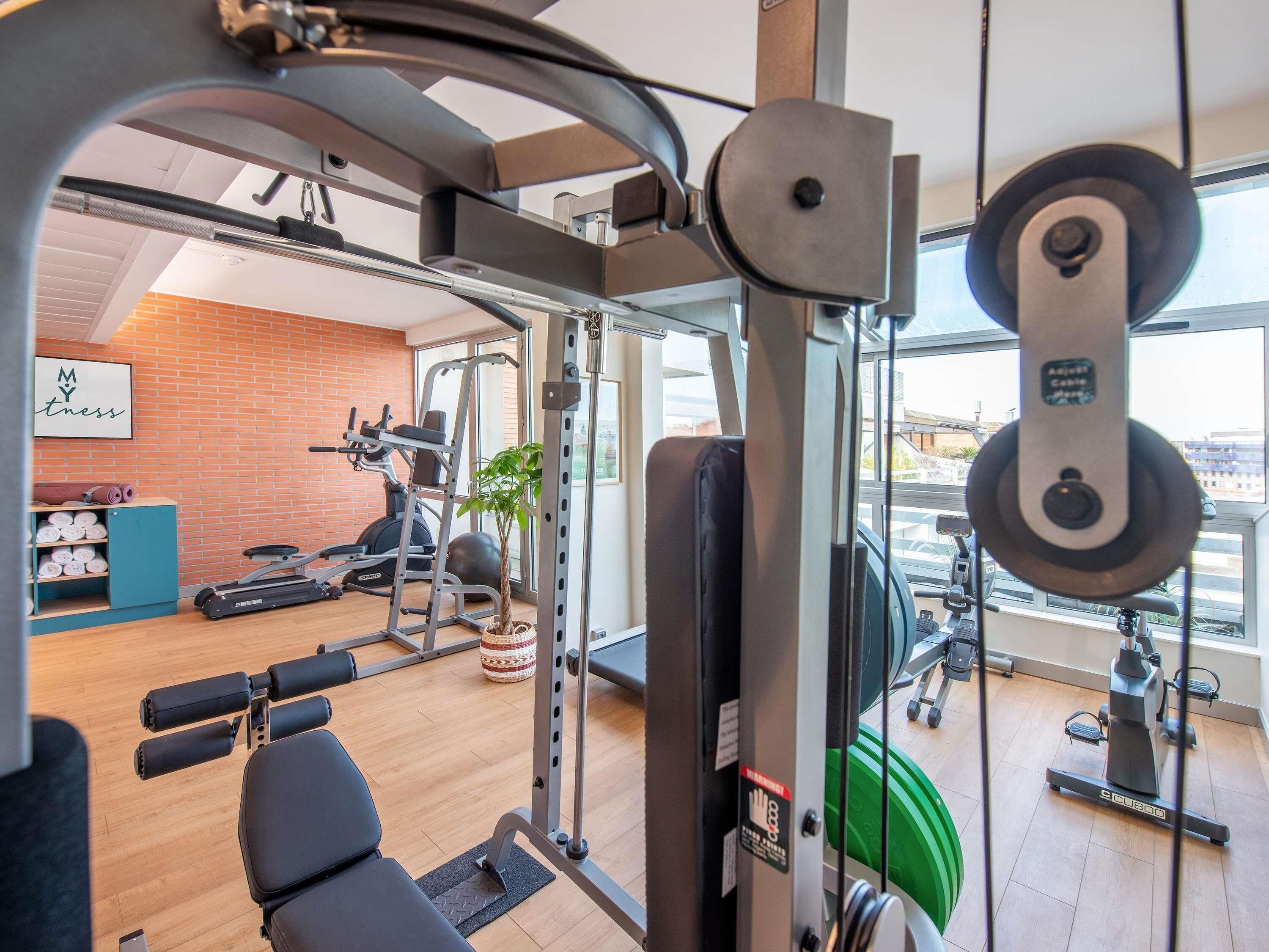 A gym with exercise equipment, a brick wall, a window, and a sign that says "My Fitness".