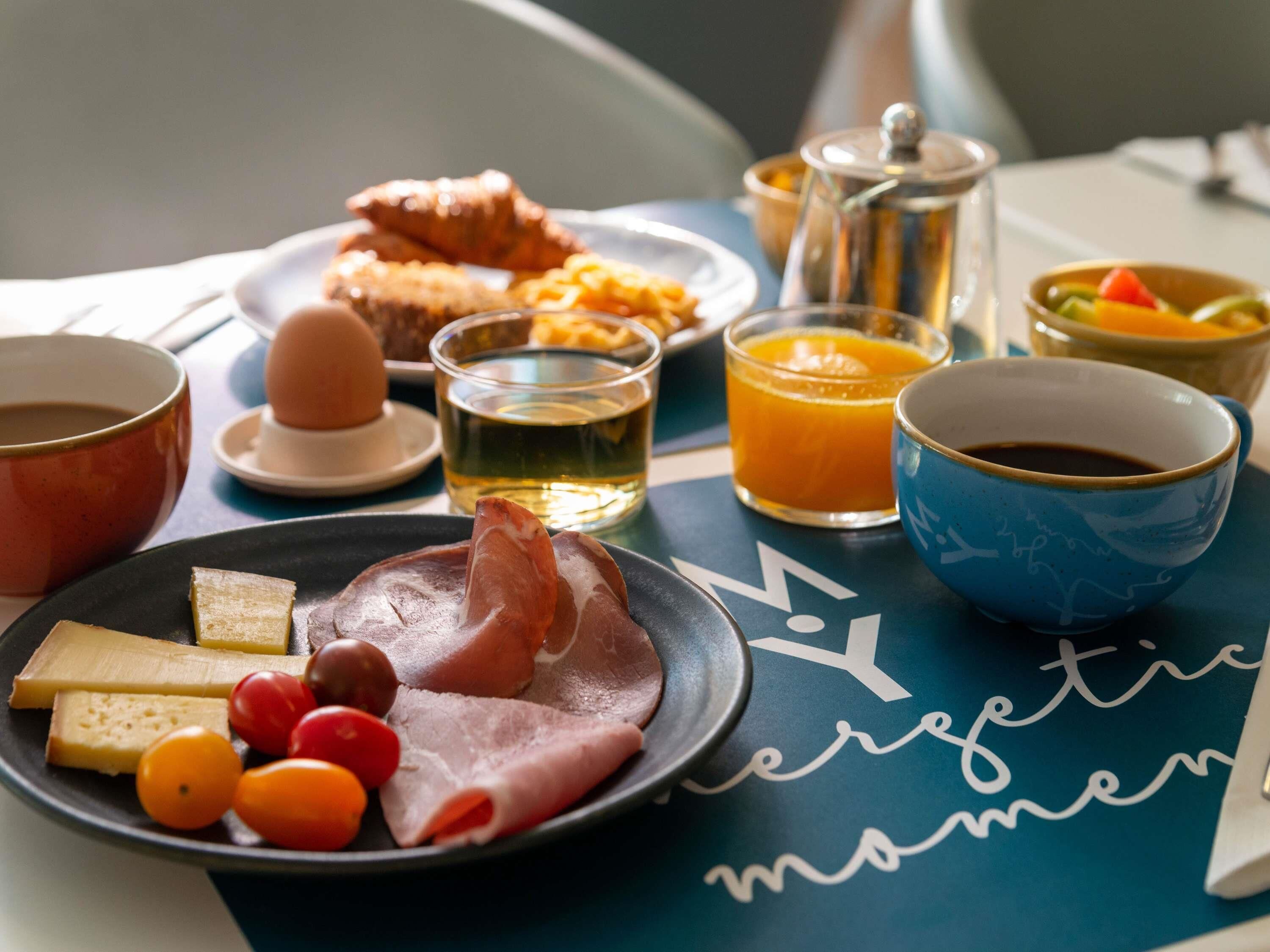 Une table de petit-déjeuner avec divers aliments, des boissons et une théière.