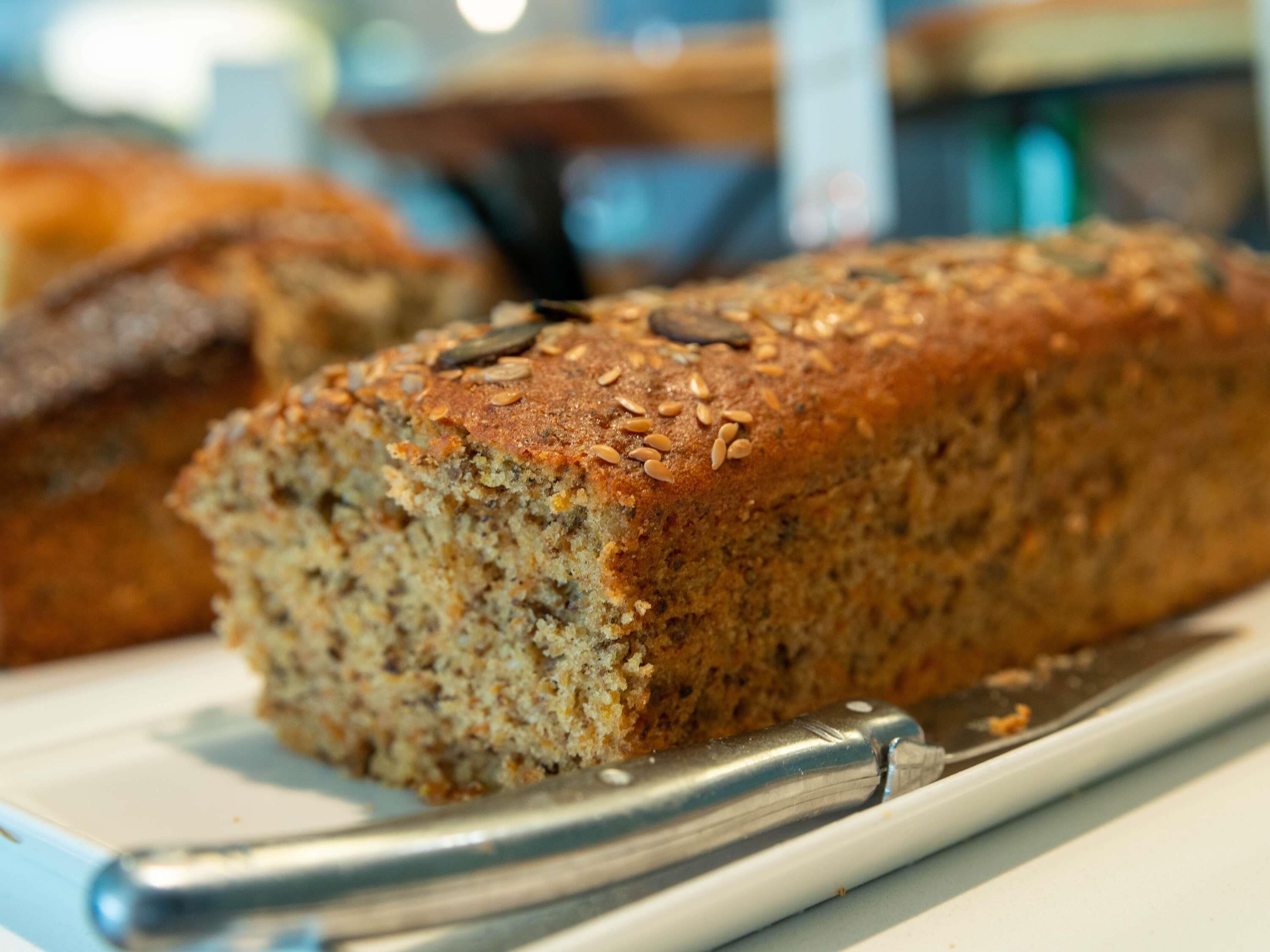 Une miche de pain parsemée de graines, posée sur une assiette, avec un couteau à côté.