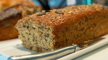 Une miche de pain parsemée de graines, posée sur une assiette, avec un couteau à côté.