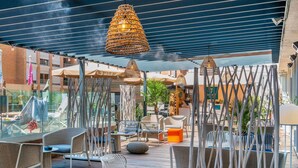 An outdoor seating area with wicker furniture, umbrellas, and hanging lamps. - Mercure Toulouse Centre Saint-Georges Hotel (Toulouse)