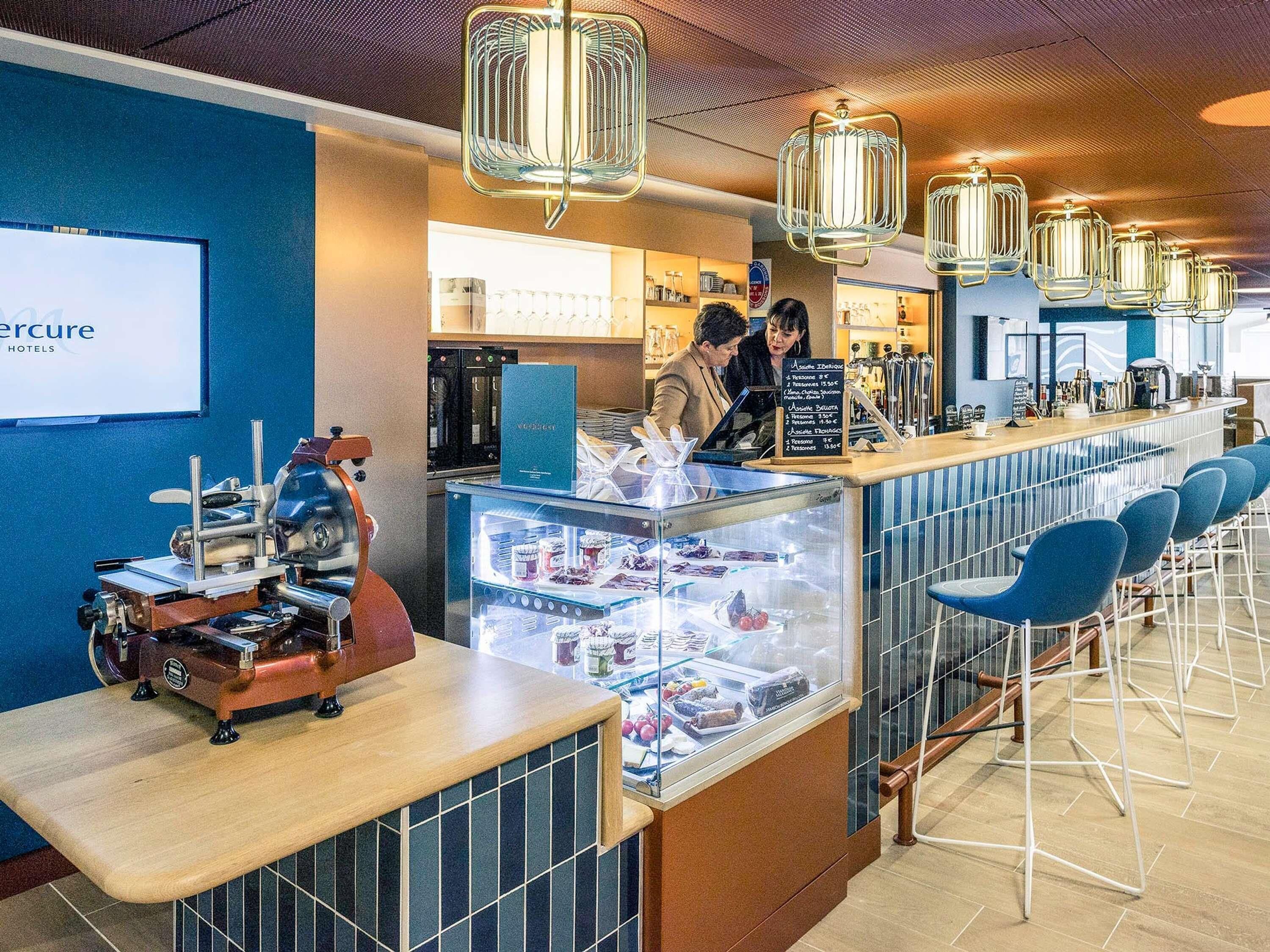 Una zona de bar con una máquina de café, una vitrina con alimentos y un panel de menú.