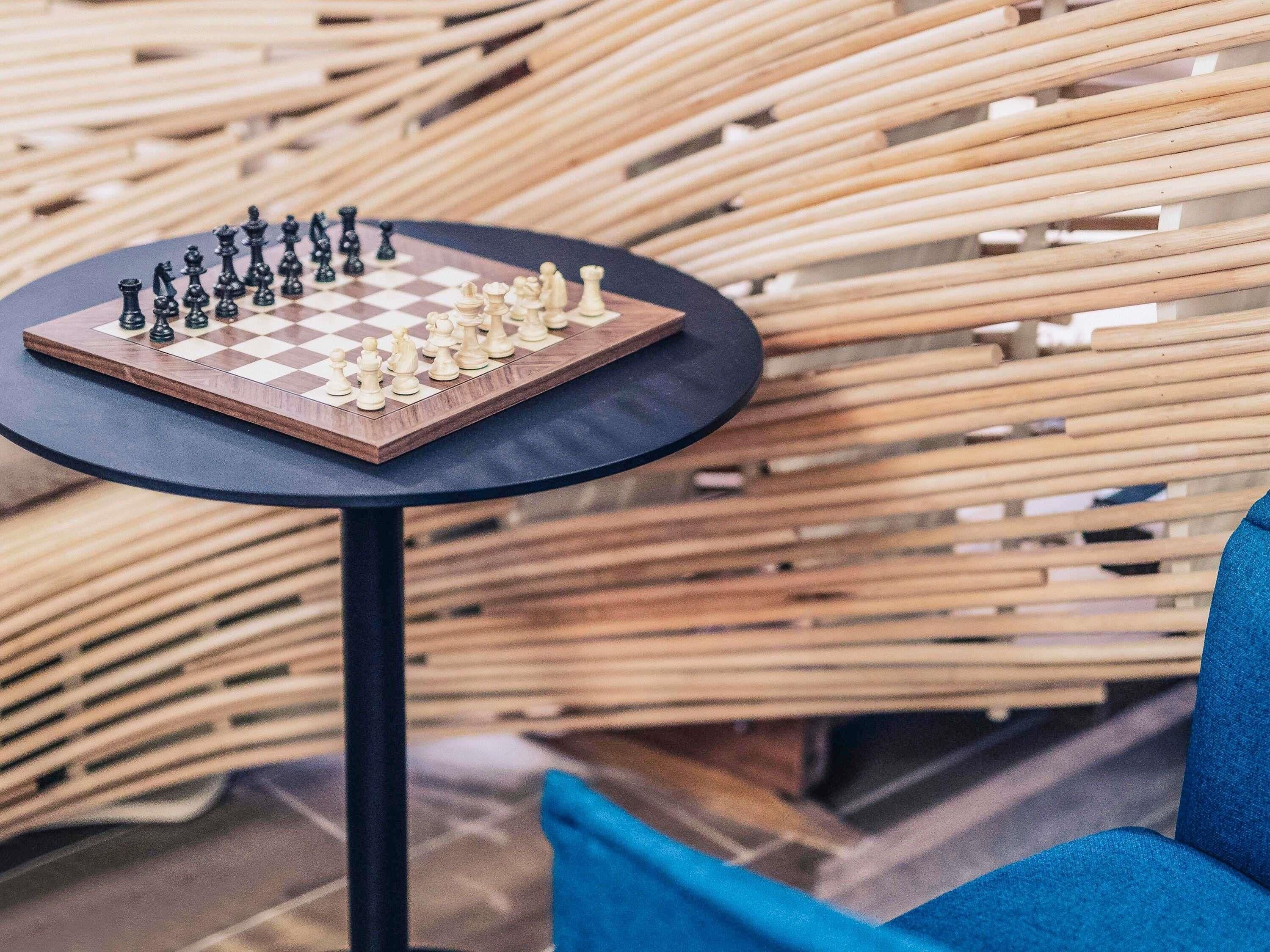 A chessboard on a round table with a woven background.