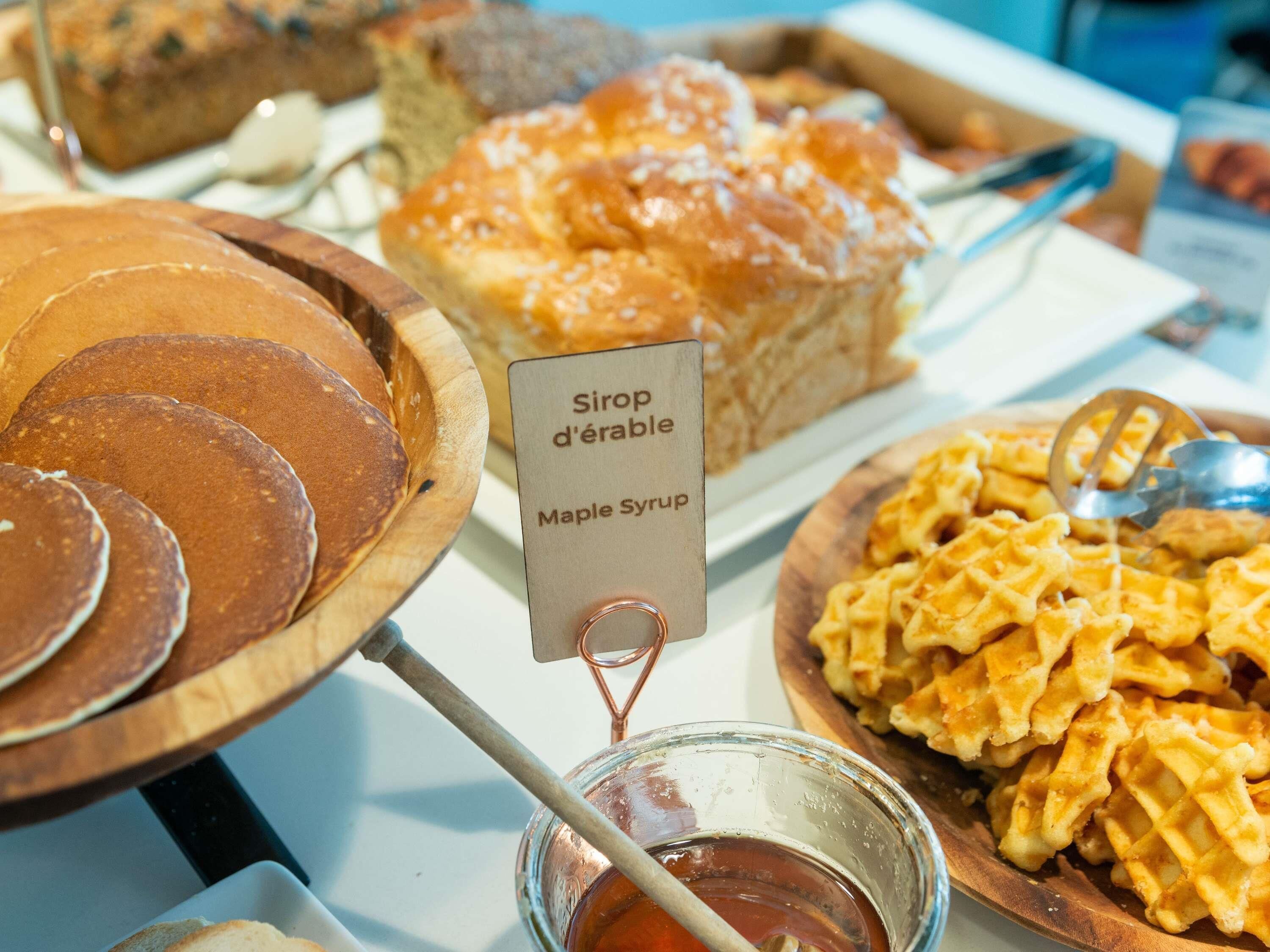 Un buffet proposant des crêpes, des gaufres et un panneau indiquant la présence de sirop d’érable.