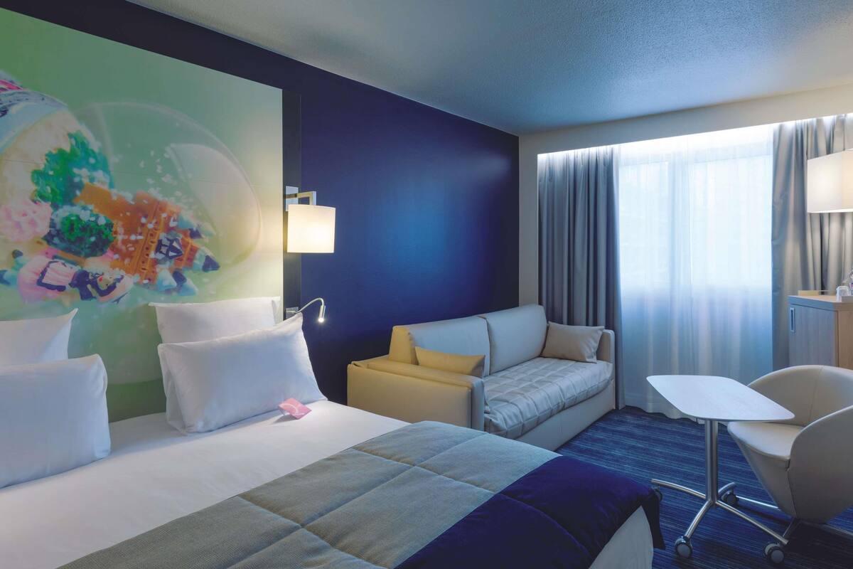 Ein Hotelzimmer mit Bett, Sofa, Schreibtisch und Sessel.