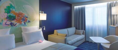 Une chambre d’hôtel avec un lit, un canapé, un bureau et une chaise.