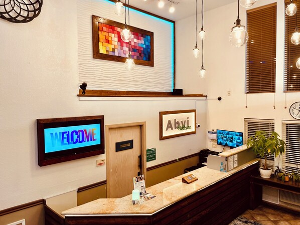 Welcome to Abvi, where guests are greeted by a warm reception area featuring a digital screen, a framed sign, and a decorative wall art piece.