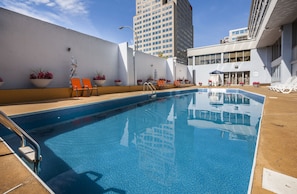 Una piscina al aire libre de temporada, sombrillas