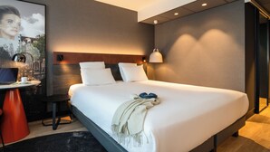 Habitación de hotel moderna con una cama grande, un escritorio con una computadora portátil y un cuadro enmarcado en la pared.