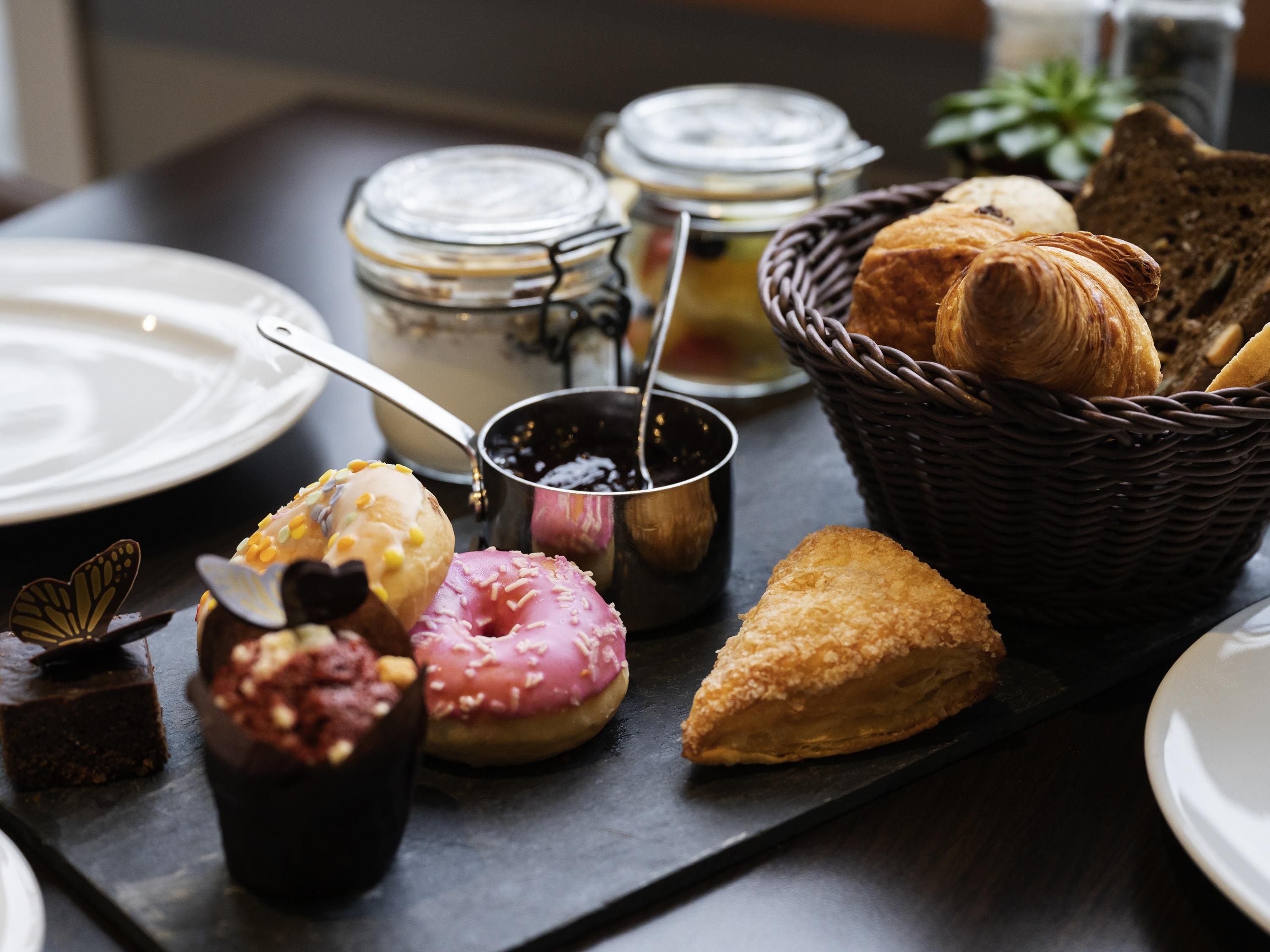 Una bandeja de desayuno con bollería, un croissant, un muffin y un postre de chocolate.