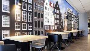 A restaurant with a mural of Amsterdam buildings, tables, and chairs.