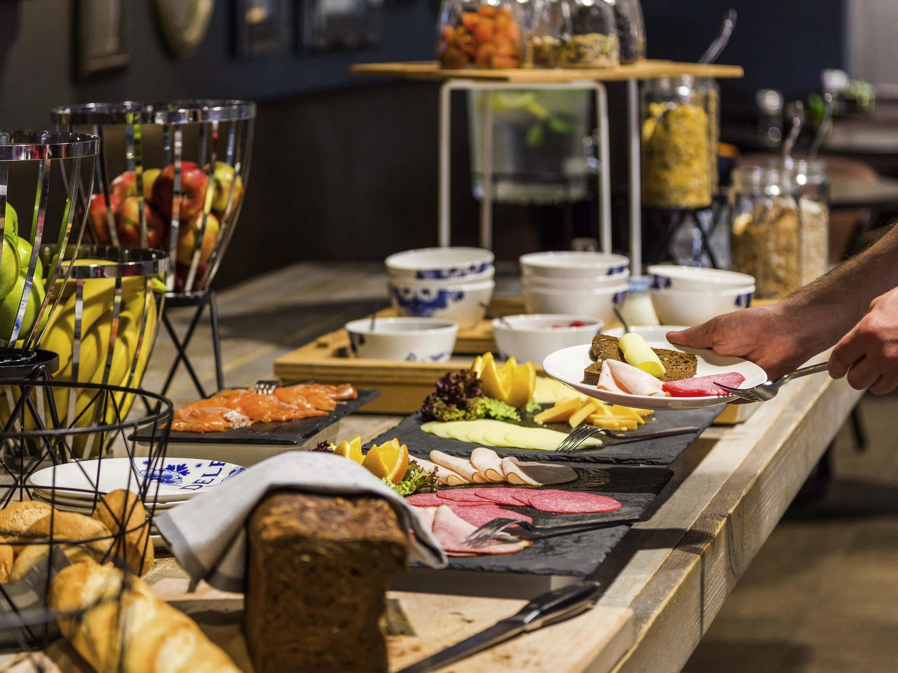 A buffet with various food items and a person serving themselves.