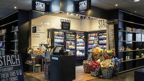 A food shop named 'Stach Foodshop' with a checkout area, shelves stocked with various products, and baskets of groceries.