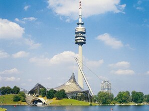 Una torre grande con un sistema de teleférico, un estadio y una masa de agua.