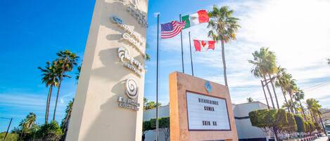 A sign with 'Welcome Comex' and 'Skin RL' text, flags, and palm trees.