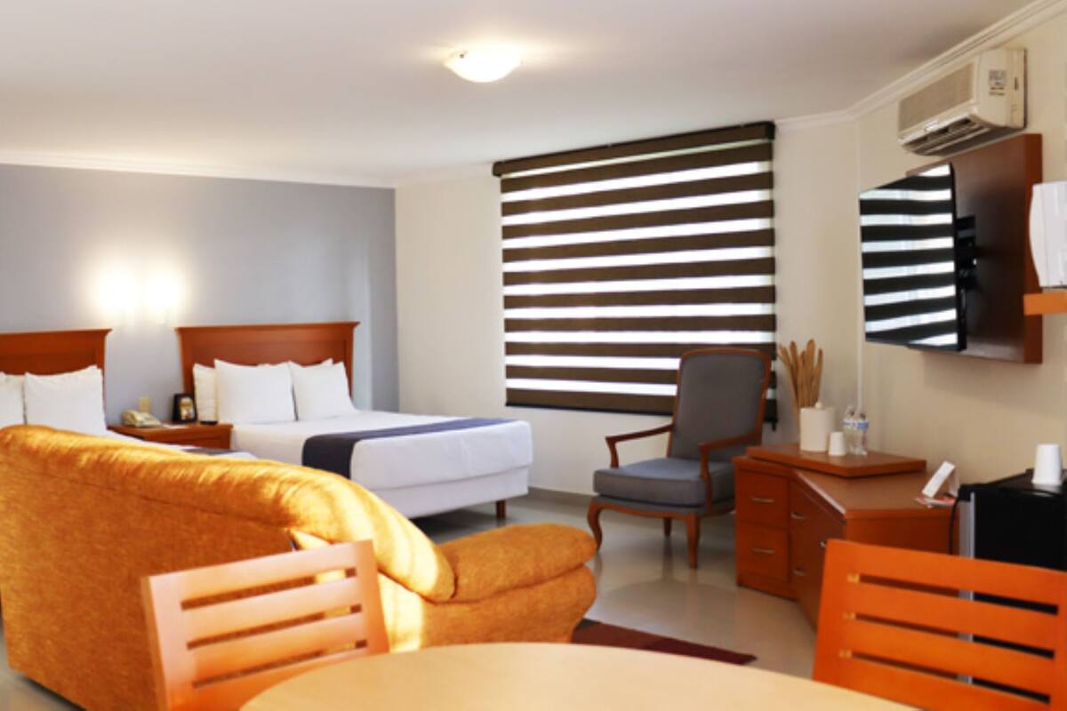 Een hotelkamer met twee bedden, een bank, een bureau en een stoel.