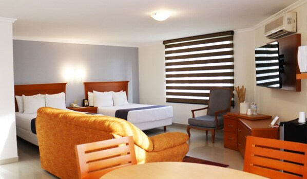 Habitación de hotel con dos camas, un sofá, un escritorio y una silla.