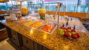 Ein Buffet mit verschiedenen Speisen, einer Obstschale und einer großen Vase.