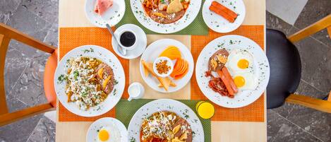 A table with various dishes, including tacos, eggs, and a drink.