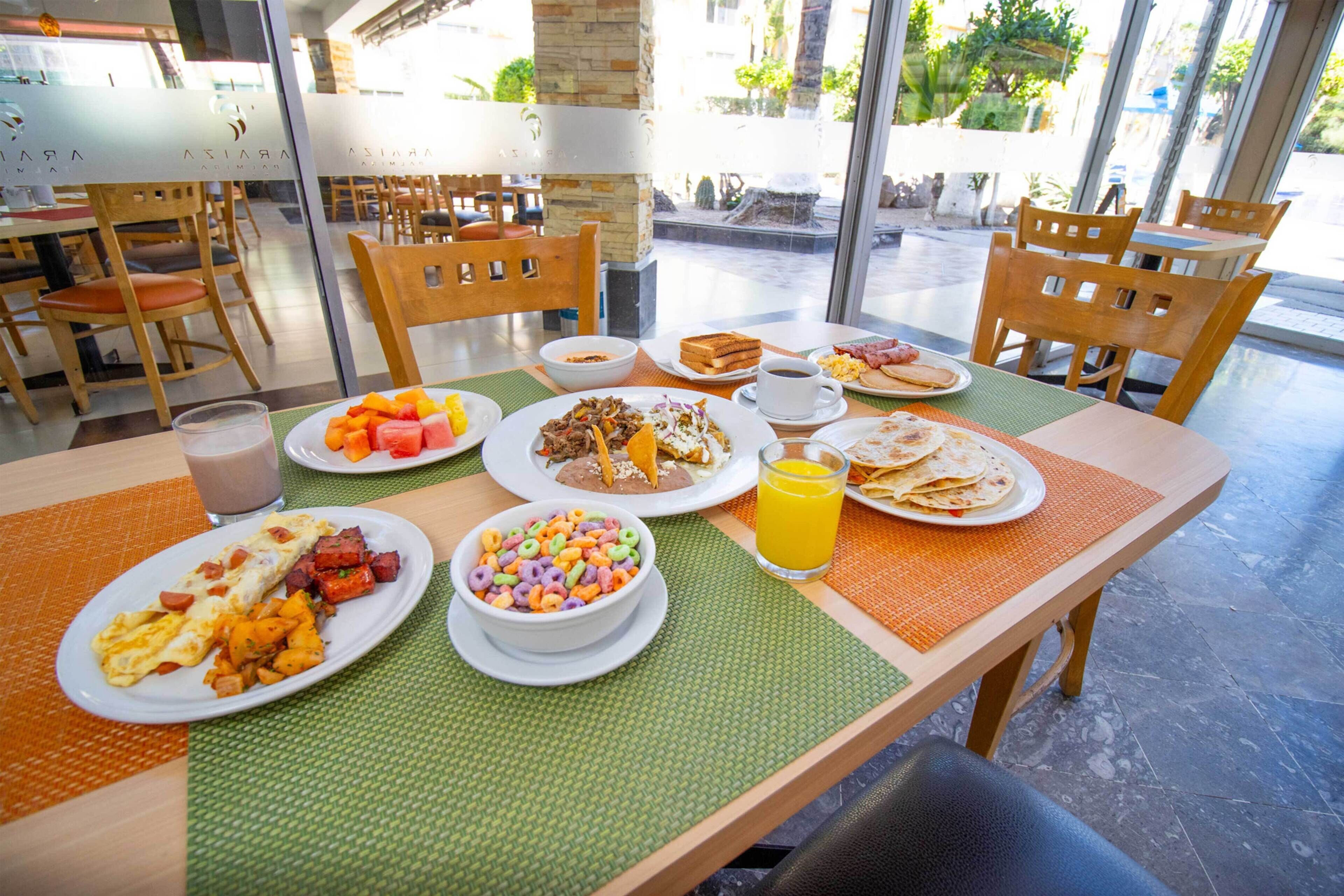 A breakfast setting with various dishes, including eggs, toast, and fruit, at a table with chairs.