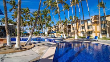 Una piscina al aire libre, sombrillas, sillones reclinables de piscina